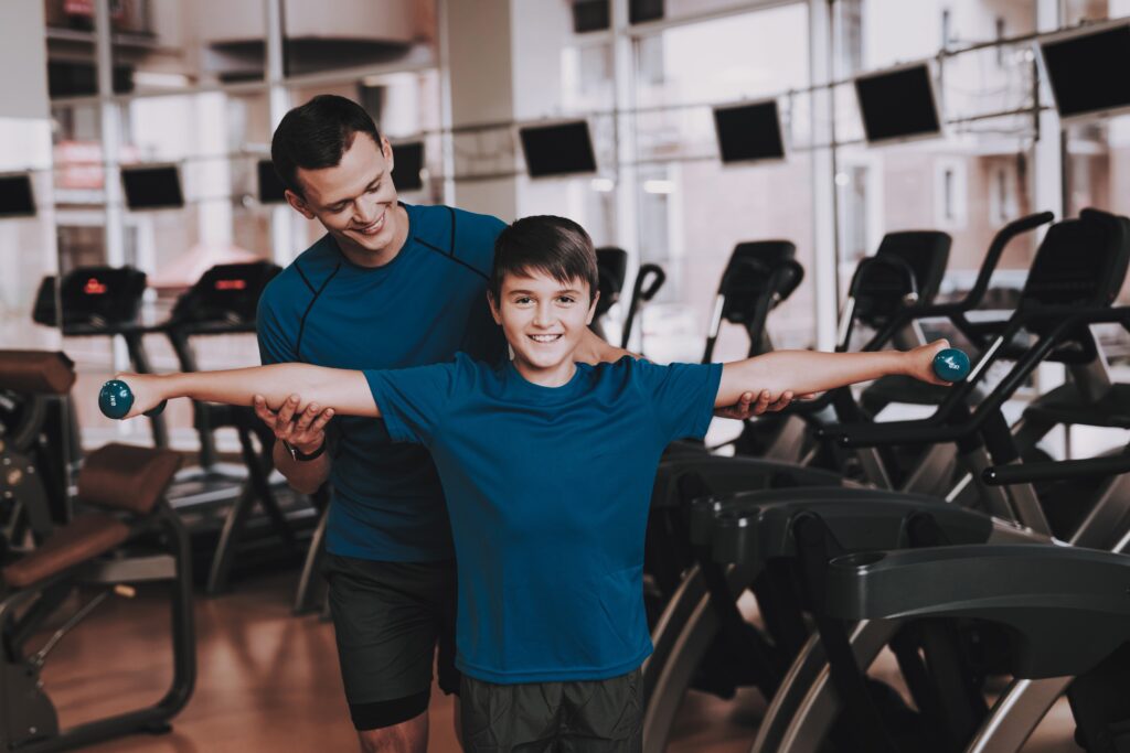 Young,Father,And,Son,Doing,Exercises,In,Sport,Club.,Healthy